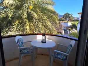 a table and chairs on a balcony with a palm tree at Appartement El Palmar Denia in Denia