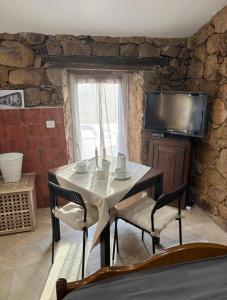 a dining room with a table and chairs and a television at Bergerie du Riccio avec piscine privée in Cauro