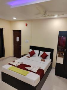 a bedroom with a large bed with red and yellow pillows at VRS Residency in Mysore