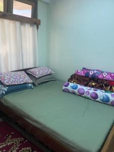 two twin beds in a room with a window at Lhamus homestay in Tawang