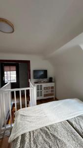 a white bedroom with a bed and a television at Cottage - Kleine alte Villa am See in Bestensee