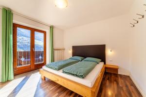 a bedroom with a large bed and a large window at Der Bognerhof - Ferienwohnungen mit beheiztem Salzwasserpool in Riffian bei Meran in Rifiano +25 photos