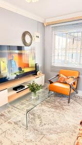 a living room with an orange chair and a television at 33OnPangolin B&B in Nelspruit