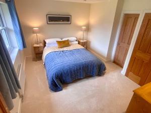 a bedroom with a bed with a blue blanket and two lamps at Braemore Walled Garden in Garve