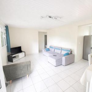 a living room with a couch and a tv at VILLA Ti-COULANGE, Verdoyante in Rivière-Pilote