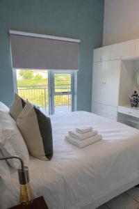a bedroom with a white bed with towels on it at Goose Valley Golf Estate D7 in Plettenberg Bay