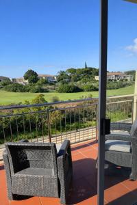 a balcony with chairs and a view of a golf course at Goose Valley Golf Estate D7 in Plettenberg Bay