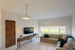 a living room with a couch and a tv at Goose Valley Golf Estate D7 in Plettenberg Bay