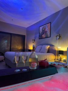 a bedroom with a bottle of wine and two wine glasses at La Maison Coloniale Suites privatives de prestige in Torreilles