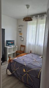 a bedroom with a bed and a desk and a television at Mais pour ce jour in Brest