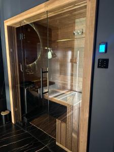 a glass door to a bathroom with a sink at Moon Luxury Apartment - Jacuzzi & Sauna in Wałbrzych