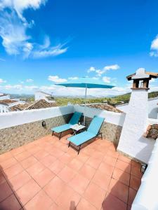 a patio with two chairs and an umbrella at Casa Isabel in El Gastor