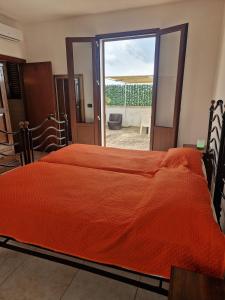 a bedroom with a bed with an orange blanket at La Cambusa B&B in Cocumola