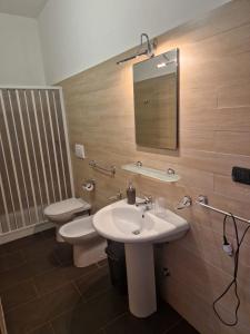 a bathroom with a sink and a toilet and a mirror at La Cambusa B&B in Cocumola