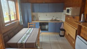 a small kitchen with blue cabinets and a microwave at Chalet Aster 3 étoiles in Arrentès-de-Corcieux