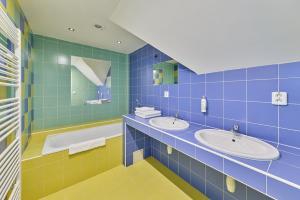 a blue tiled bathroom with two sinks and a tub at Garnet Penzion in Olomouc +40 photos