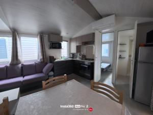 a living room with a purple couch and a kitchen at La Carabasse / Mazet 69 in Vias