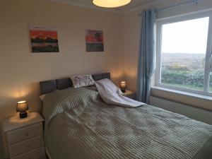 a bedroom with a bed with two night stands and a window at Gweedore Seaview Cottage in Bun na Leaca