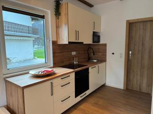 a kitchen with white cabinets and a sink and a window at Apartman Bor in Kiseljak +3 photos