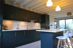 a kitchen with dark blue cabinets and white counter tops at Thrush Cottage in Schull