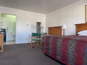 a hotel room with a bed and a table and a chair at Economy Inn Motel in Kingman