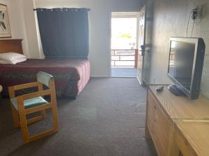 a bedroom with a bed and a tv and a chair at Economy Inn Motel in Kingman