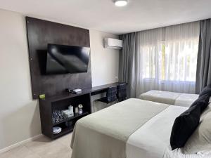 ein Hotelzimmer mit zwei Betten und einem Flachbildfernseher in der Unterkunft Suite del sol in Pinamar
