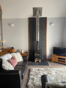 a living room with a couch and a wood stove at Bwlch Cottage in Gwaynynog