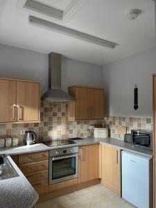 a kitchen with wooden cabinets and a stove top oven at Bwlch Cottage in Gwaynynog