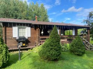 a log cabin with a porch and two trees at Pikkjärve puhkemaja in Tilsi