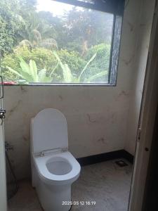 a bathroom with a toilet with a large window at Sada Niwas in Ucassaim