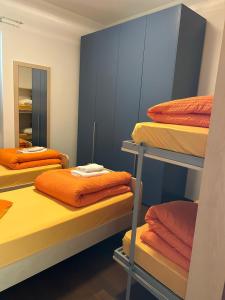 a room with three bunk beds with orange sheets at Luxury casa Margherita in Pianello Del Lario