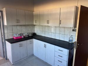 a kitchen with white cabinets and a black counter top at Albam residency kuruman in Kuruman +7 photos