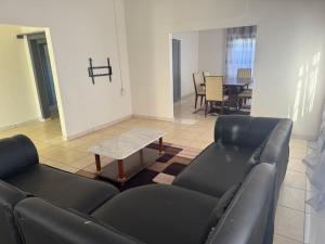 a living room with black leather furniture and a table at Albam residency kuruman in Kuruman
