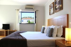 um quarto com uma grande cama branca e uma janela em Vicentina Hotel em Aljezur