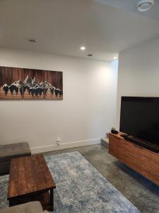 a living room with a flat screen tv and a coffee table at Black Arrow Chalet in Courtenay