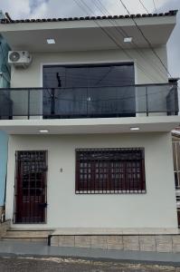 a white house with a balcony and two windows at Casa Bragança suíte in Bragança