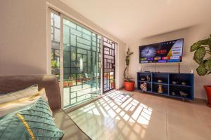 a living room with a large window and a tv at Casa Hidalgo By Mi Querido Coyoacán in Mexico City
