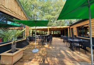 a patio with tables and chairs and a green umbrella at De Hooglander in Zuidwolde