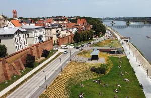 a group of people sitting on the grass next to a river at Zakątek Spokoju in Toruń