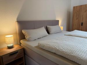 a bed with two pillows and a lamp on a table at Sonnenufer Apartment & Wein III in Bernkastel-Kues