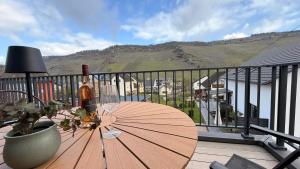 a table with an umbrella and a bottle of wine on a balcony at Sonnenufer Apartment & Wein III in Bernkastel-Kues