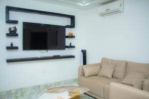 a living room with a couch and a flat screen tv at La MAISON SEONE PREMIUM in Abidjan