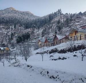 a group of houses on a snow covered mountain at Moksh Jibhi Retreat in Jibhi