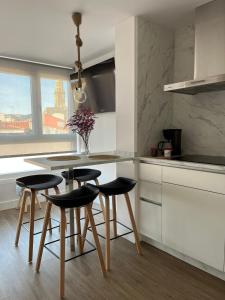 a kitchen with a table and four stools in it at Casa da Fonte in Rianjo