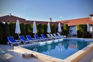 a swimming pool with chairs and umbrellas at Guest house Zlateya in Madara