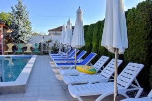 a row of lounge chairs with umbrellas next to a pool at Guest house Zlateya in Madara