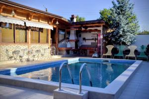 a swimming pool with chairs and a house at Guest house Zlateya in Madara +10 photos
