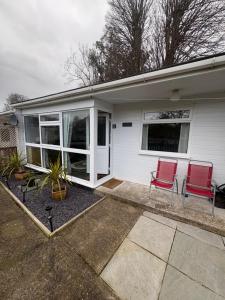 two red chairs sitting outside of a house at Modern retreat in Caernarfon