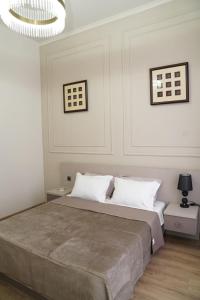 a bedroom with a bed with white walls and a chandelier at EL hotel in Kutaisi +51 photos